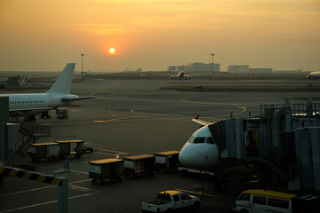 Fototapeta na wymiar Planes on airport tarmac in dramatic sunset light.