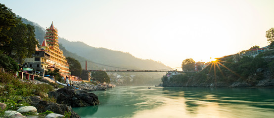 Spectacular view of the Lakshman Temple bathed by the sacred river Ganges at sunset.  - obrazy, fototapety, plakaty