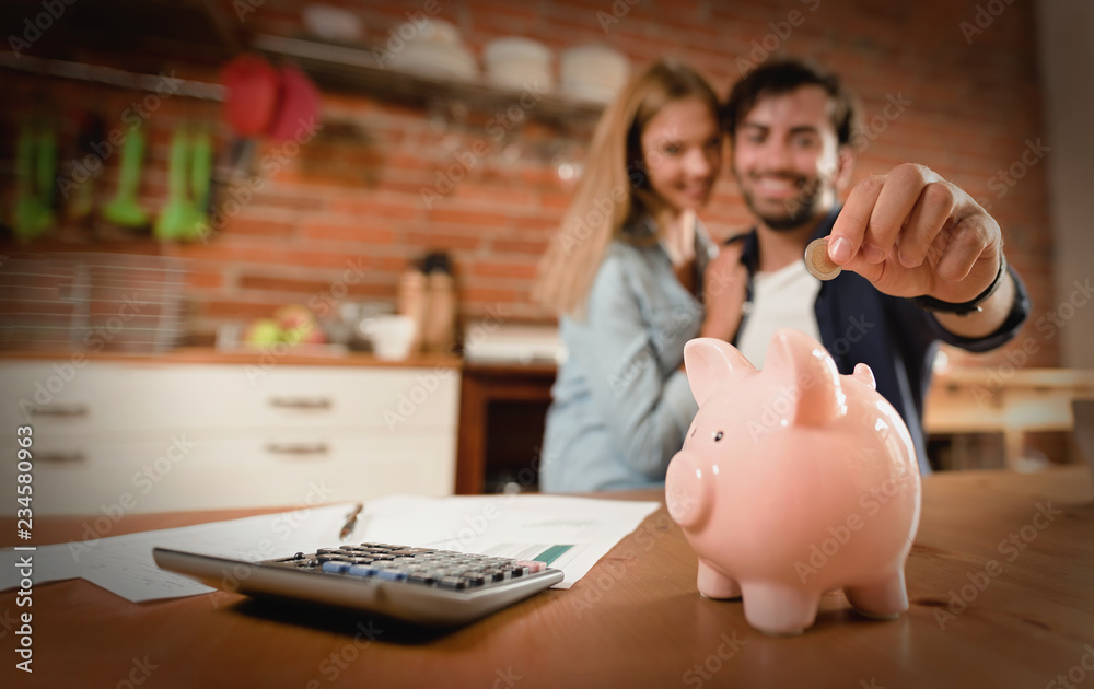 Wall mural happy couple inserting coin in piggybank