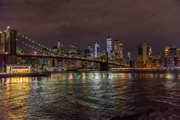 Fototapeta na wymiar The Lights of Manhattan Surround the Brooklyn Bridge as It Crosses New York City's East River
