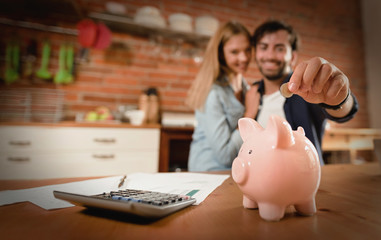 Happy couple inserting coin in piggybank