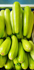 Green fresh squashes in a wooden box on the market street