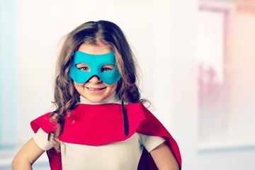 Portrait of  beautiful little girl in superhero costume on light