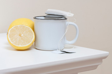 LIMÓN Y TAZA DE TÉ SOBRE MESA BLANCA