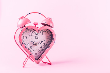 Heart shaped clock on pink background.  Valentines day and love infitity and duration concept