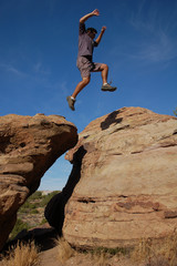Young man leaping on high rock formations at Vazquez Rocks in California