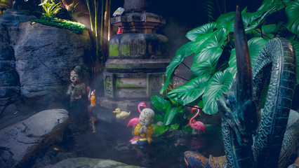 Steamy foggy mossy pond with stone figures. Pink flamingos and buddhas
