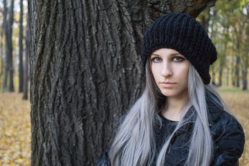 Portrait of young woman near tree in the autumn forest