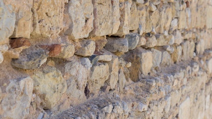 A very old, rough, worn, stone wall in Portugal, Algarve region.