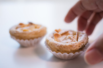 Delicious Portuguese Almond Pastry Tart being picked up from a white table.