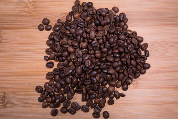 Fresh roasted natural coffee beans close up from above looking straight down on natural wood surface.