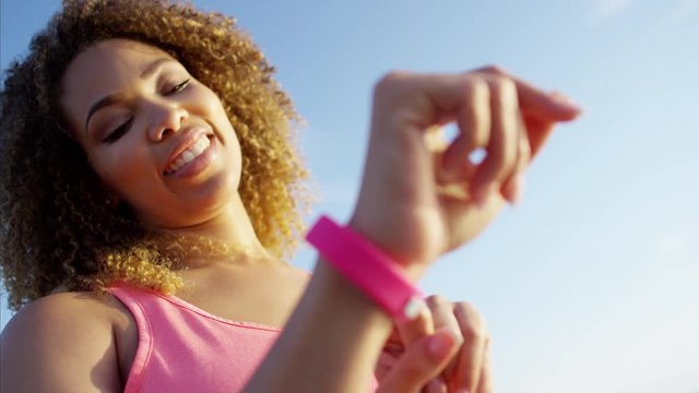 Active voluptuous Ethnic African American female using interactive technology on wrist for pulse and calories during fitness 