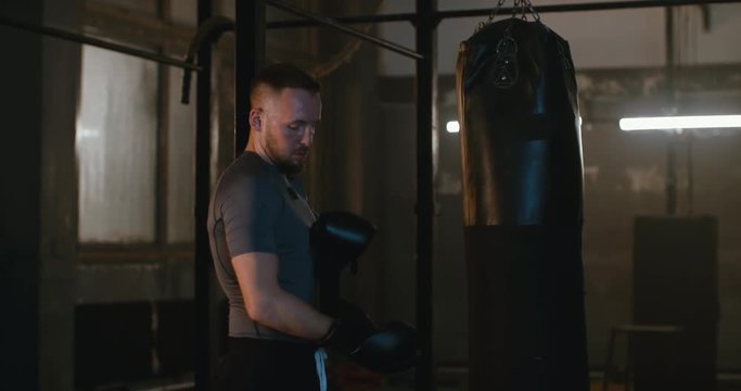 MS Caucasian male puts on boxing gloves in a boxing studio before training. 4K UHD