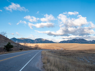 View of Road With Sharp Turn to the Right Into the Mountains With Wind Turbine in the Distance