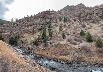View of Mountain Stream Flowing Next to Tall Rocky Mountain