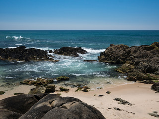 Beautiful rocky beach on sunny day with clear blue water and blue cloudless sky in Vila do Conde, Porto region, Portugal
