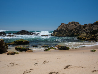 Fototapeta na wymiar Beautiful sunny beach in Portugal with cloudless blue sky and clear water waves crashing on rocks. Vila do Conde, Porto.