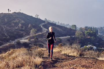 Fototapeta premium Beautiful Caucasian White Woman Runs on a Trail in the Morning Sunlight