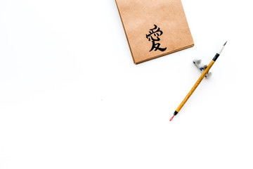 Chinese traditional calligraphy concept. Asian hieroglyph symbol in craft paper notebook near...