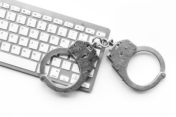 Cyberfraud concept. Handcuff near keyboard on white background top view copyspace closeup