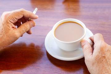 Elderly man with cup of coffee and cigarette