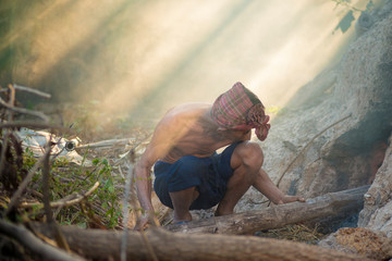 An old man burning firewood. A man's hand is laying wood into the furnace and fireplace