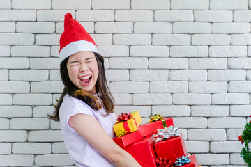Girl wearing a Santa hat holding gifts near a Christmas tree in Christmas and New Year festival. Party Concept.