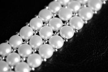 White pearl necklace on a dark background close up. Black and white