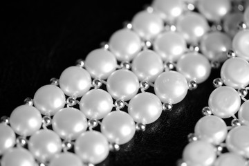 White pearl necklace on a dark background close up. Black and white