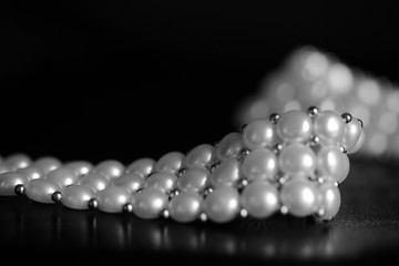 White pearl necklace on a dark background close up. Black and white