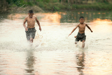 Two Asian boys friends running,playing in the water in summer sunny day.Freedom of life. friendship and freedom concept. 