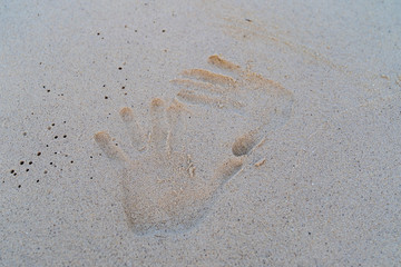 Hand print on the white sand.