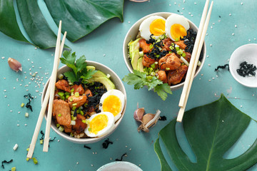 Two poke bowl fried rice chicken fillet eggs top view Asian food - obrazy, fototapety, plakaty