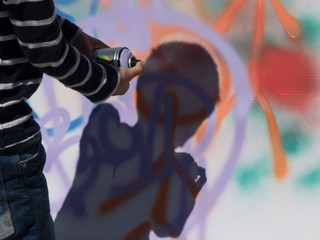 Young boy artist using spray wall graffiti background