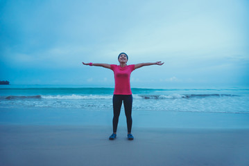 Asian women running workout jogging on the beach in the morning. extend the arms relax.