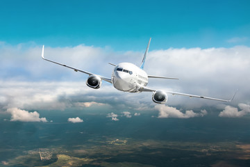Obraz premium Samolot pasażerski latać w zachmurzone chmury i błękitne niebo.