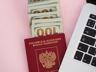passport and money and laptop, pink background