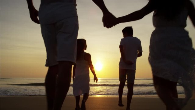Silhouette of Latin American family having fun on the ocean beach at sunset