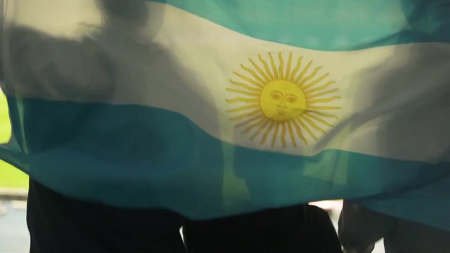 Child with parents jumping with Argentinian flag, cheering for national team