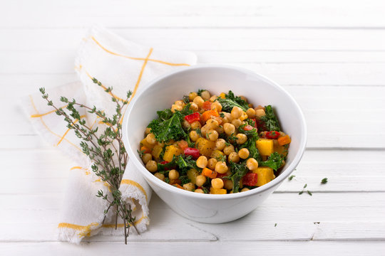 Homemade ragout with pumpkin, carrots, sweet peppers, tomatoes, chickpeas, kale and thyme in a white bowl on a white background. delicious healthy food