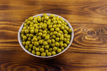 Bowl with canned green peas  on wooden table. Top view