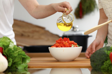 Closeup of human hands cooking in kitchen. Mother and daughter or two female friends cutting vegetables for fresh salad. Friendship, family dinner and lifestyle concepts