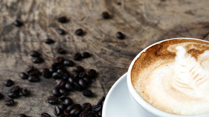 Cappuccino or latte art coffee. Free hand pouring some foam of milk on top. A white ceramic cup on the wood table with some coffee beans. The best food and drink in the world. Fresh energy everyday.