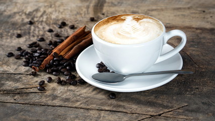 Cappuccino or latte art coffee. Free hand pouring some foam of milk on top. A white ceramic cup on the wood table with some coffee beans. The best food and drink in the world. Fresh energy everyday.