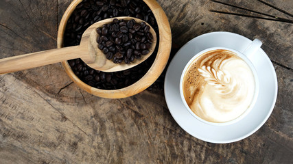 Cappuccino or latte art coffee. Free hand pouring some foam of milk on top. A white ceramic cup on the wood table with some coffee beans. The best food and drink in the world. Fresh energy everyday.