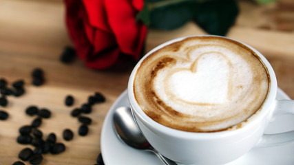 Latte art and cappuccino with hearts made from milk on the wood table with roasting coffee beans. Beverage and breakfast menu with hot coffee at the cafe shop. A cup of capuccino art.