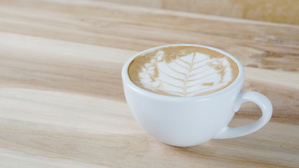 Cappuccino or latte art coffee. Free hand pouring some foam of milk on top. A white ceramic cup on the wood table with some coffee beans. The best food and drink in the world. Fresh energy everyday.