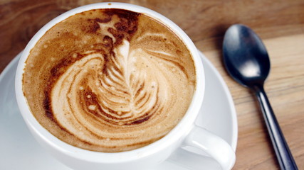 Cappuccino and latte art on the wood table. Free hand pouring some milk on the coffee. Morning breakfast with coffee.
