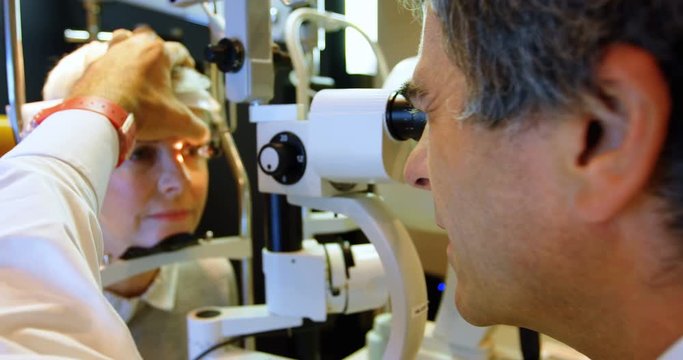 Optometrist examining patient eyes with slit lamp 4k