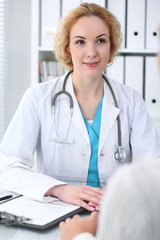 Happy blonde female doctor and patient discussing medical examination results. Medicine, healthcare and help concept